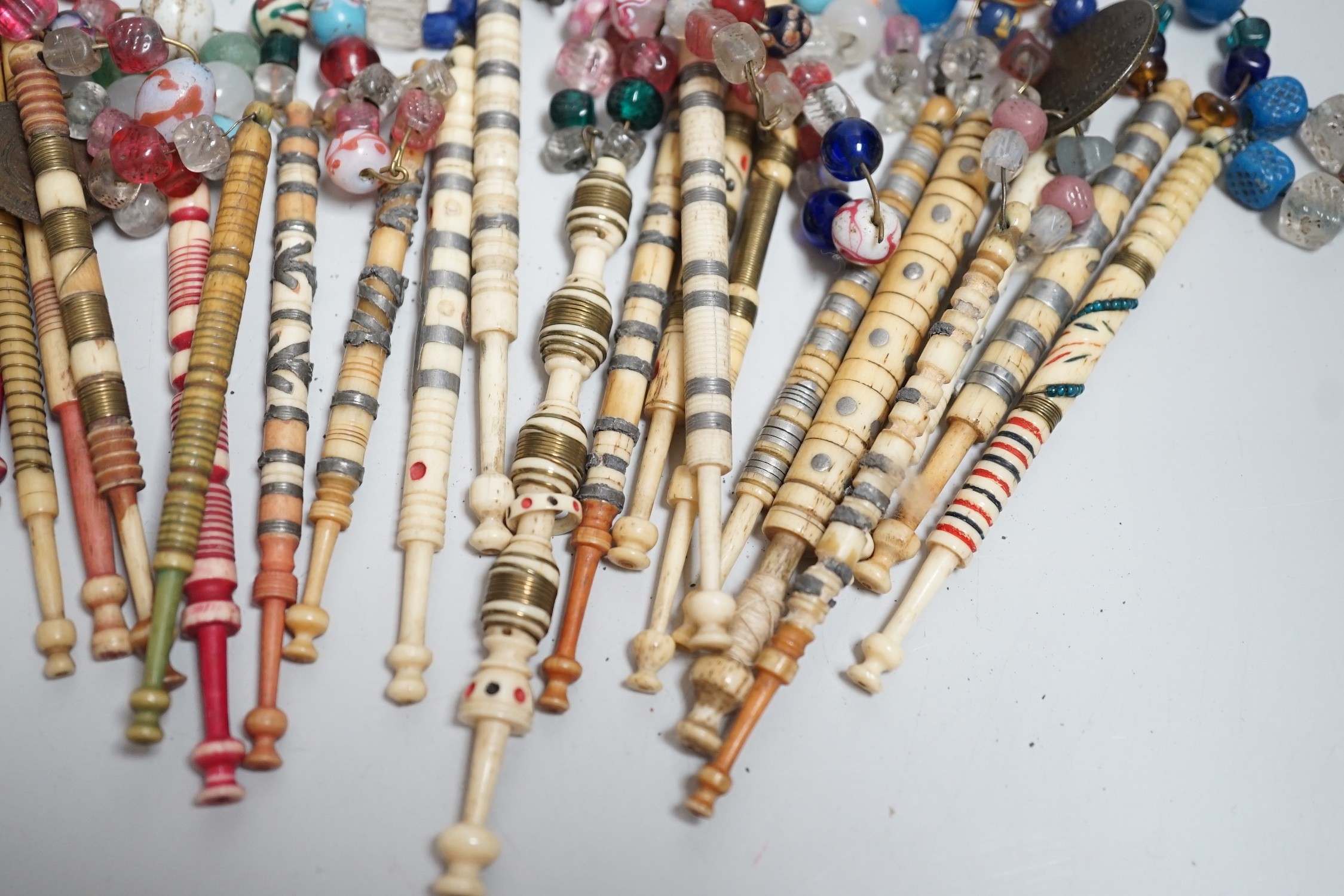 Twenty one 19th century stained and turned bone lace bobbins with glass bead tops and thirteen ornate bone and metal decorated lace bobbins with bead tops (35)